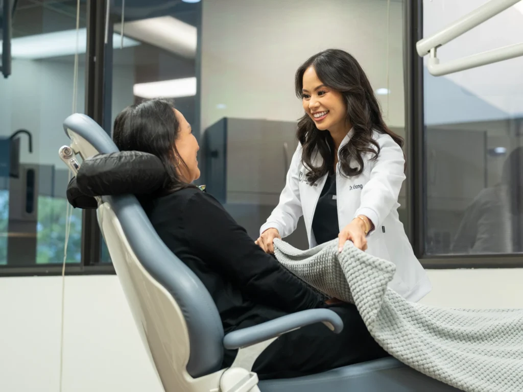 Dr. Khong providing a comforting blanket to a patient in the dental chair | Conroe Dental Associates | Conroe, TX