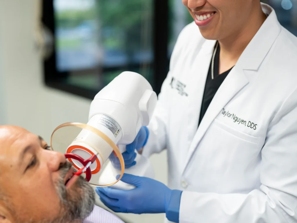 Dr. Nguyen utilizing a modern handheld portable dental X-ray machine for a patient | Conroe Dental Associates | Conroe, TX