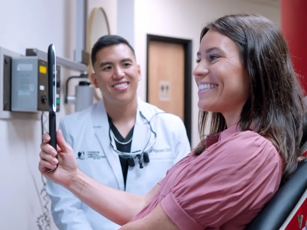 Happy patient smiling in the mirror after cosmetic dentistry at Conroe Dental Associates | Cosmetic dentistry in Conroe, TX